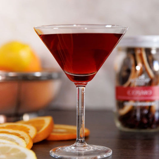 Cosmo cocktail in a martini glass with fresh citrus slices and infusion kit background