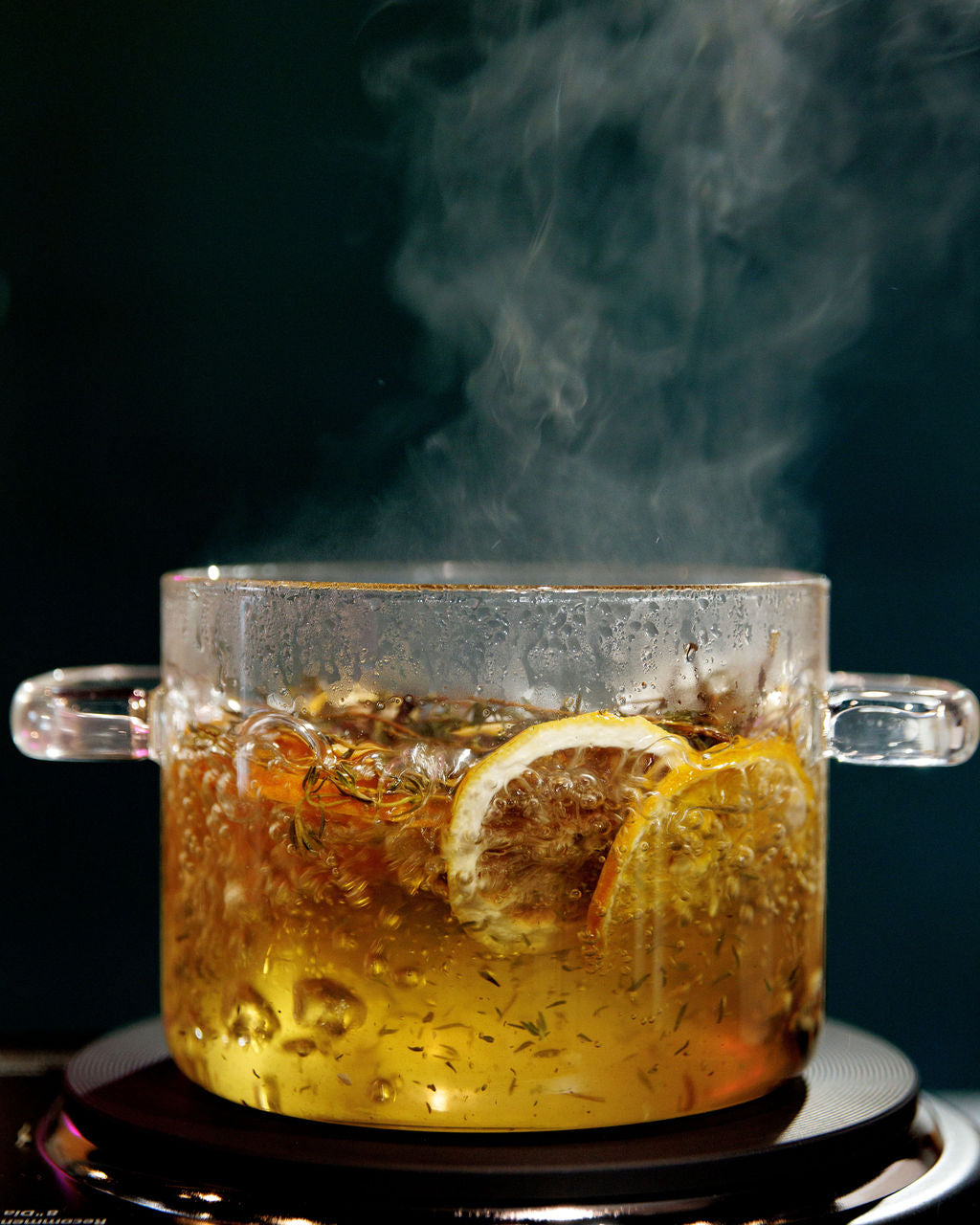 Hot simmer pot in a glass pot with steam on a dark background for thanksgiving aroma