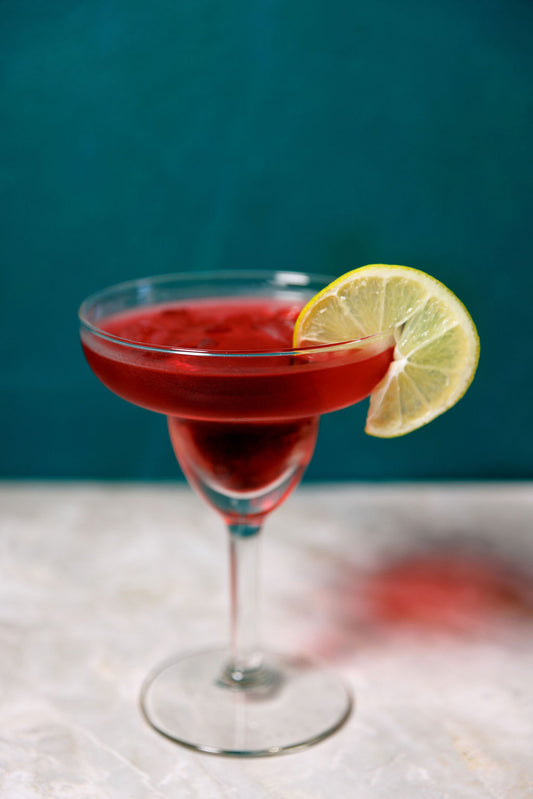 Cherry Limeade cocktail Margarita glass with fresh lime Garnish on white and green backdrop
