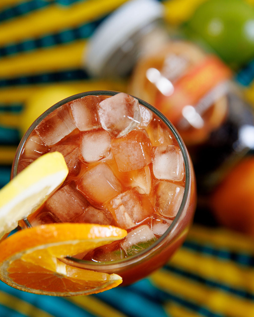 Glass of sangria with lemon and orange slices on a colorful background