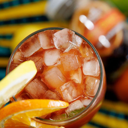 Glass of sangria with lemon and orange slices on a colorful background