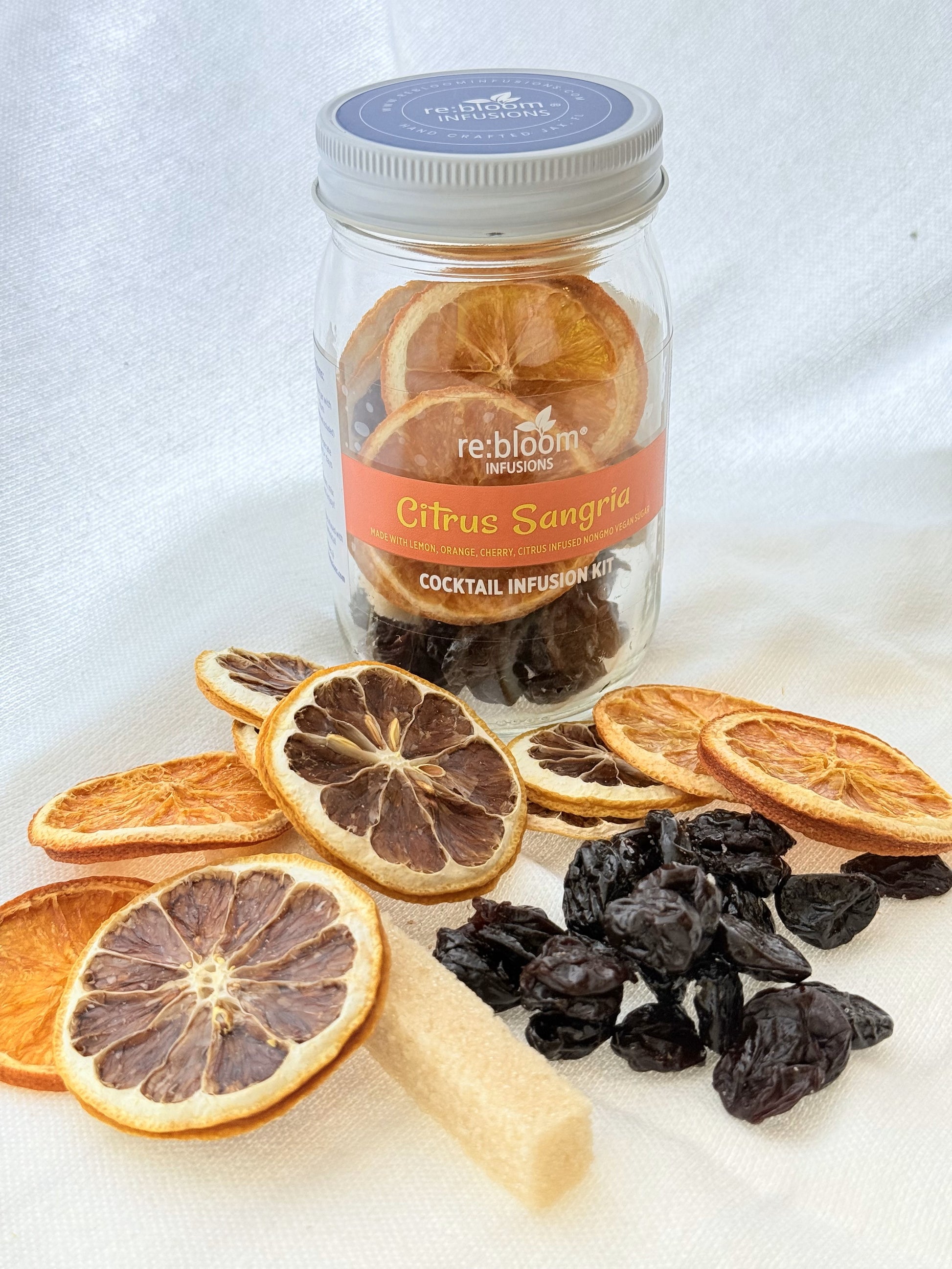 Jar of re:bloom Citrus Sangria cocktail infusion kit with dried oranges and cranberries on a white background