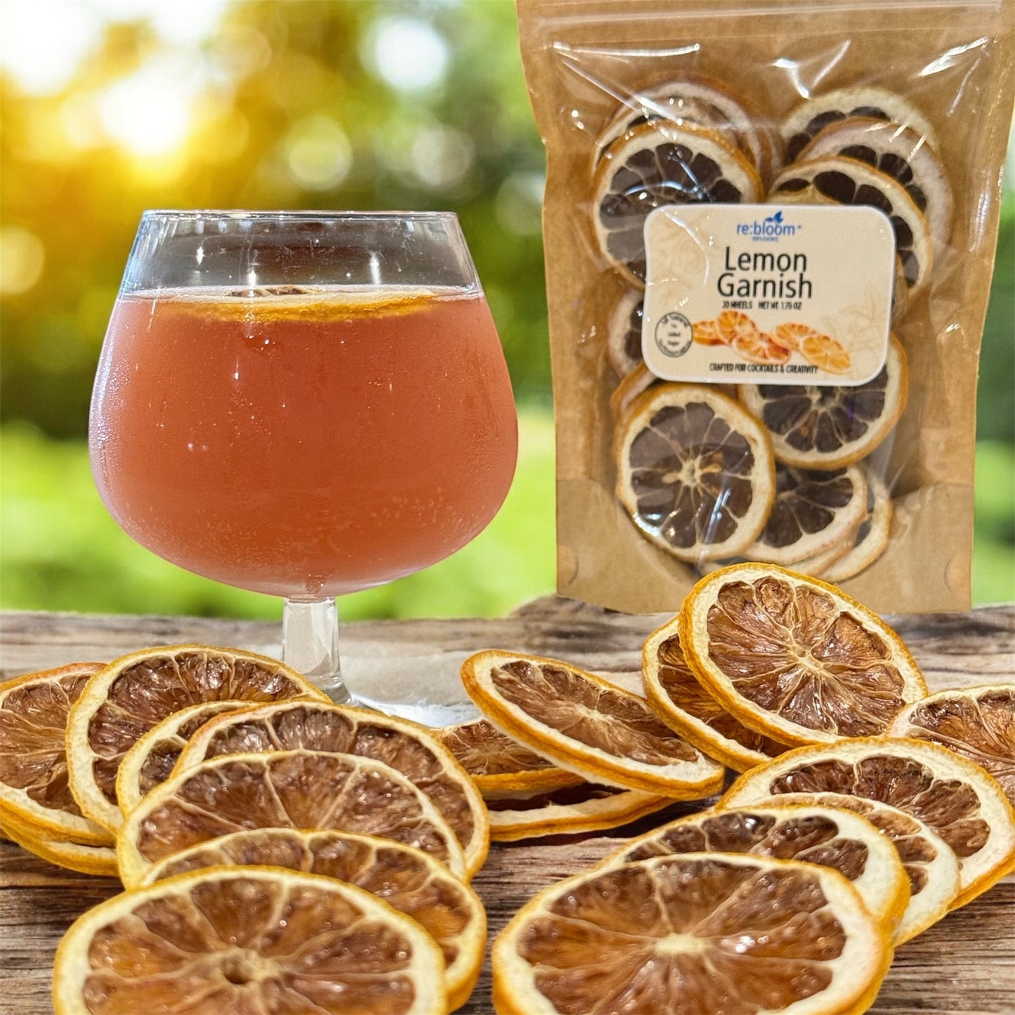 Dried lemon slices on a wooden surface with a glass of amber liquid and a package labeled 'Lemon Garnish'.