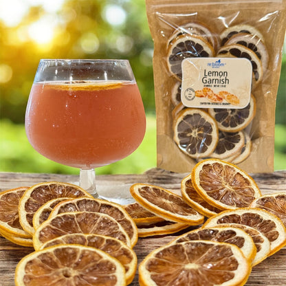 Dried lemon slices on a wooden surface with a glass of amber liquid and a package labeled 'Lemon Garnish'.