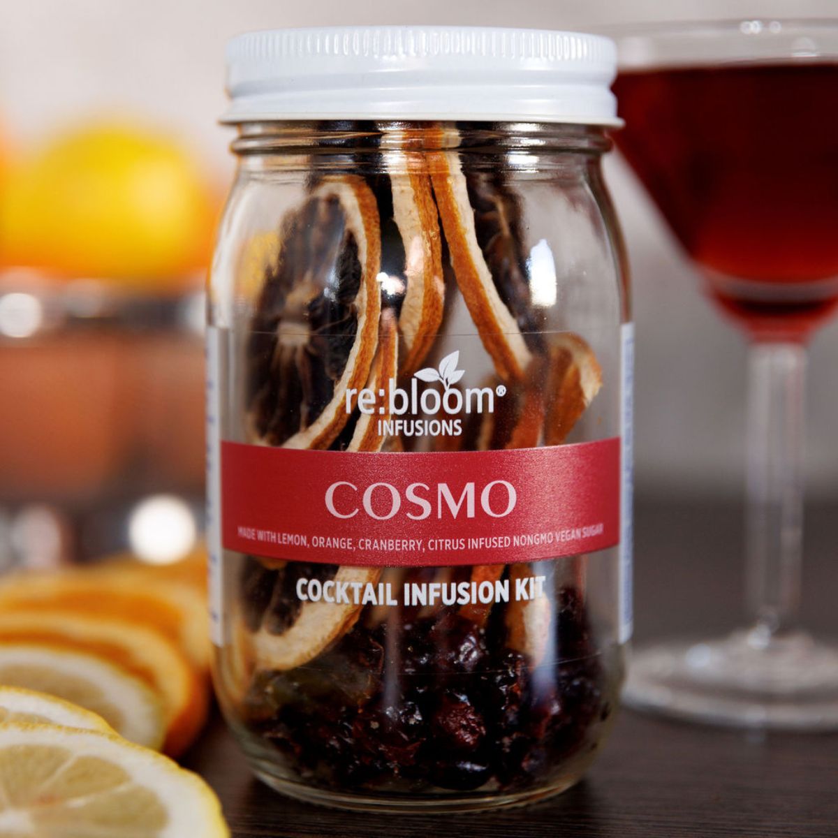 Cosmo cocktail infusion kit jar with citrus slices and martini glass background