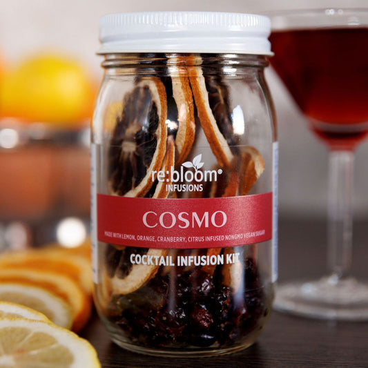 Cosmo cocktail infusion kit jar with citrus slices and martini glass background
