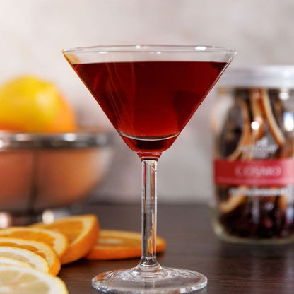 Cosmo cocktail in a martini glass with fresh citrus slices and infusion kit background