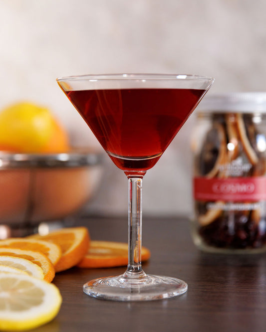 Cosmo infusion cocktail in a martini glass with fresh citrus around the cup