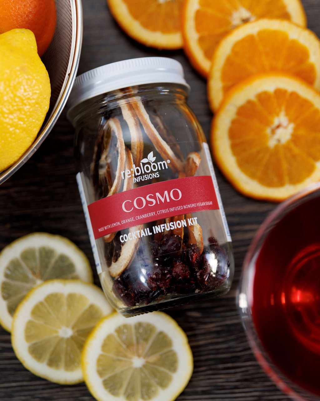 Cosmo infusion cocktail jar surrounded by fresh citrus 
