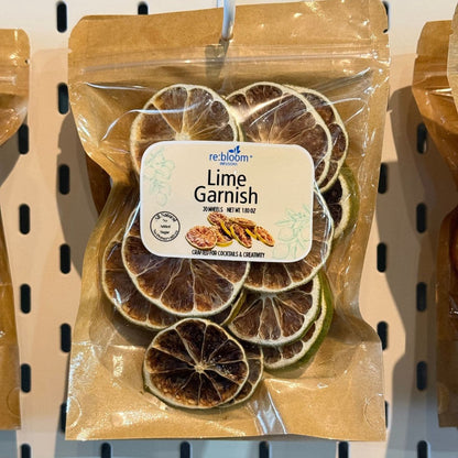 A package of re:bloom Lime Garnish dried lime slices in a clear resealable bag with a kraft paper pouch, hanging on a pegboard.