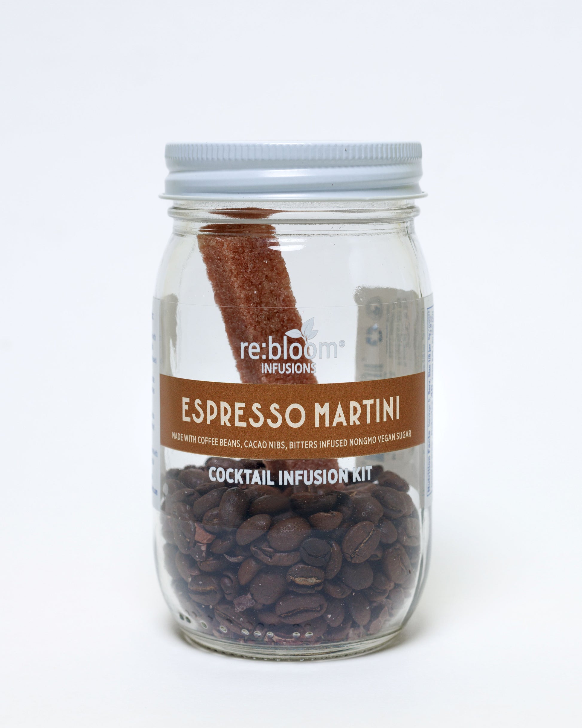 Espresso Martini cocktail infusion kit with coffee beans, cacao nibs and bitters infused sugar bar in a glass jar on a white background.