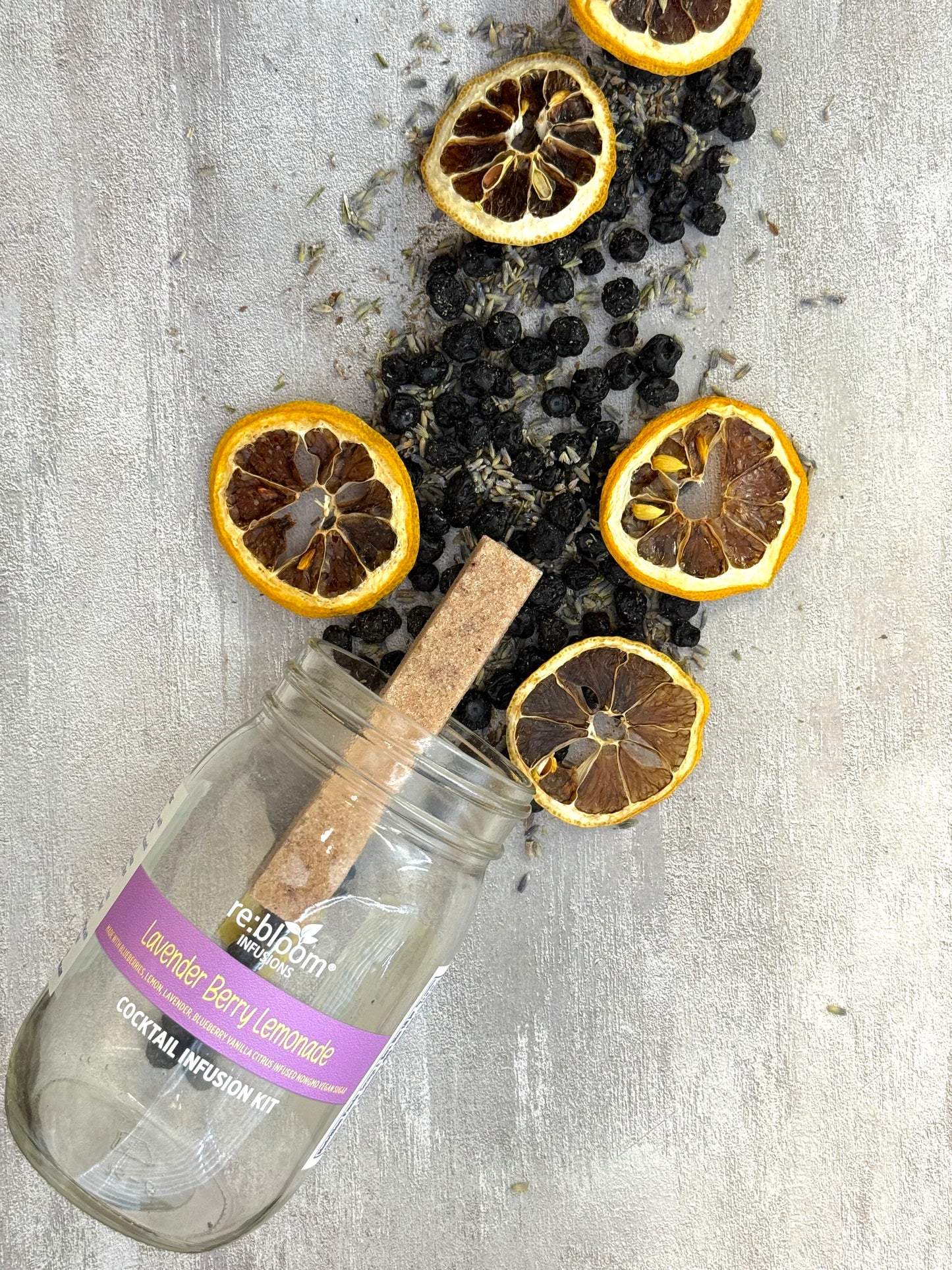 Lavender Berry Lemonade cocktail infusion kit with dried lemons and berries on a textured surface