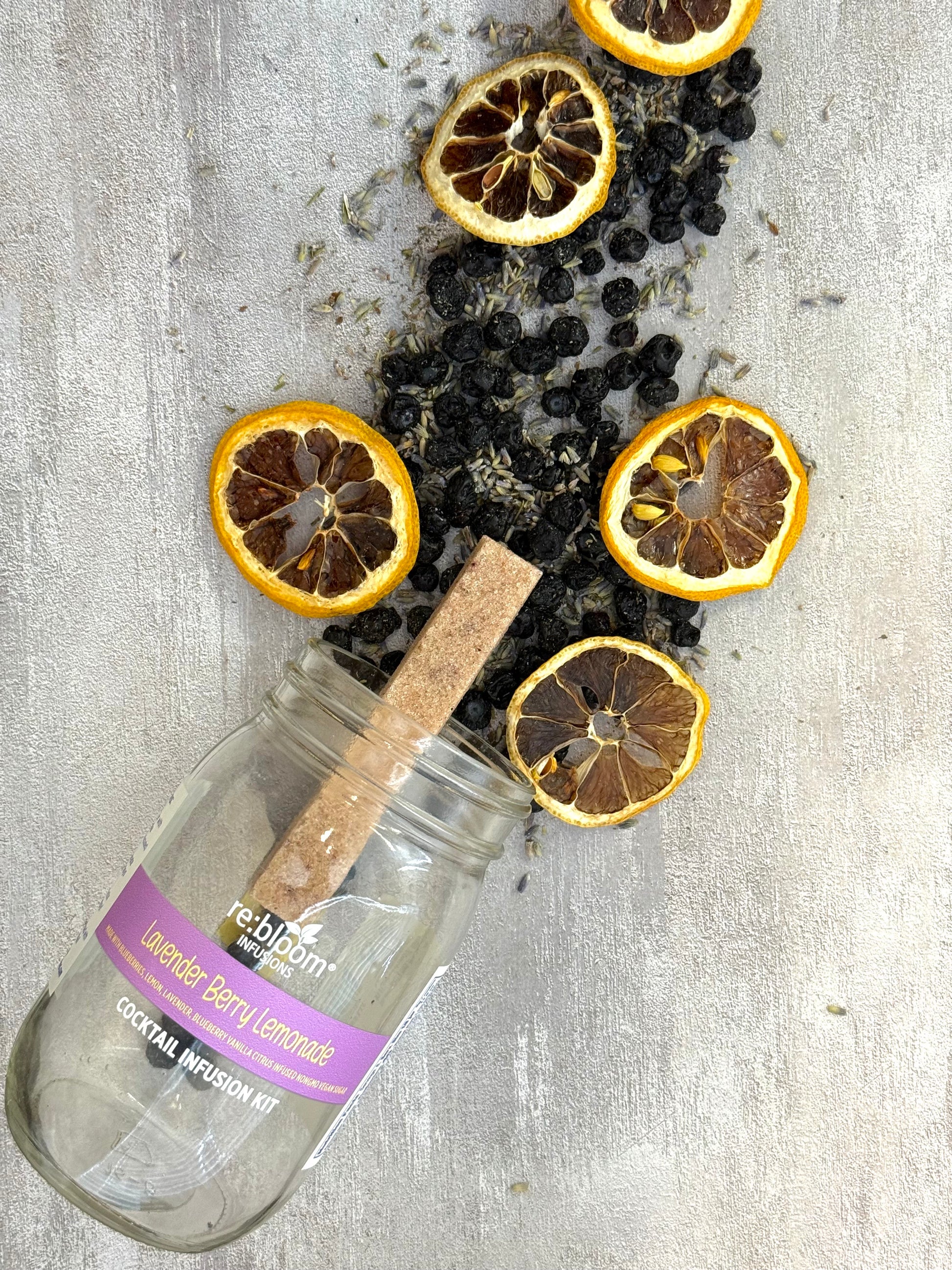 Lavender Berry Lemonade cocktail infusion kit with dried lemons and berries on a textured surface