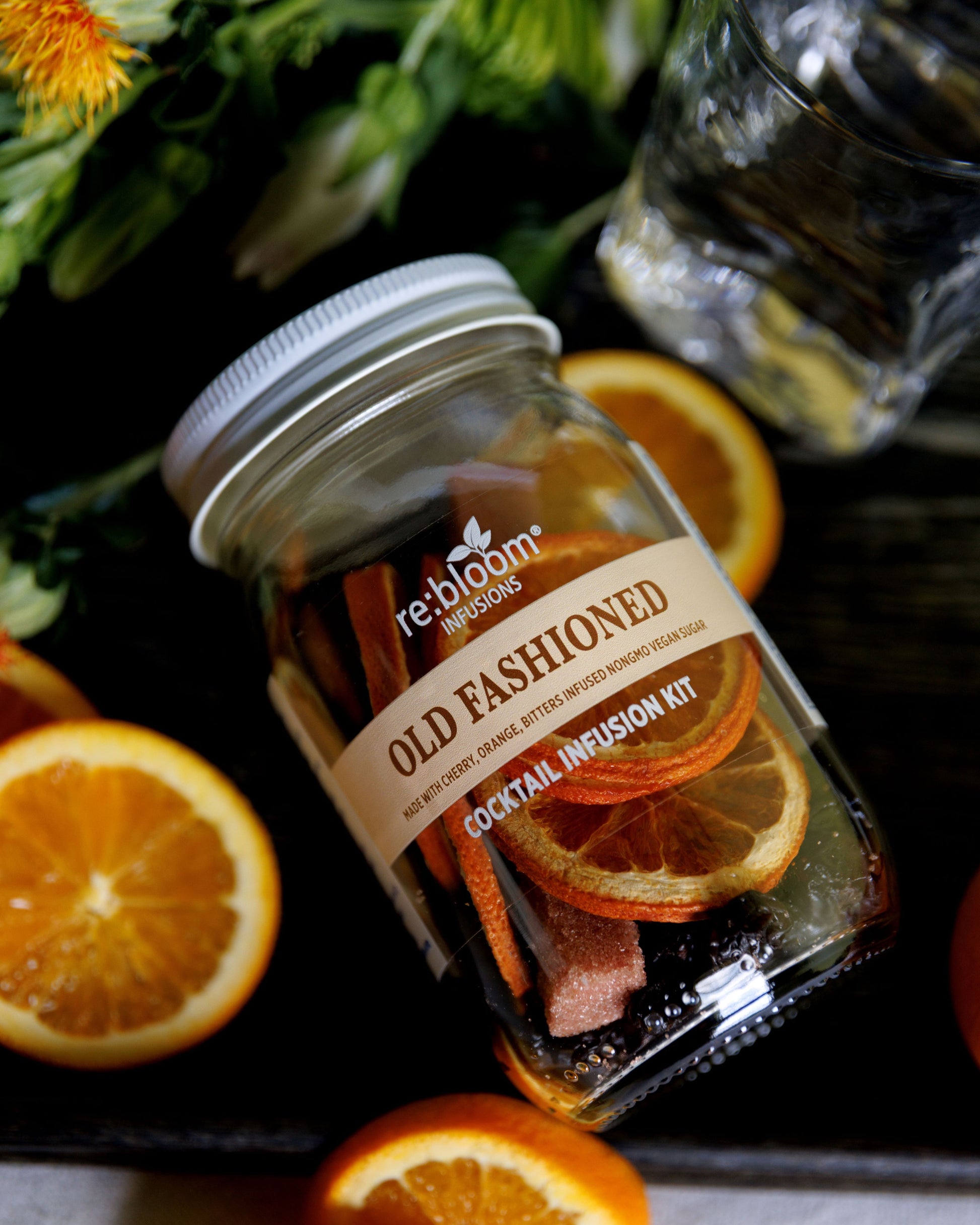 Old  Fashioned cocktail infusion kit with oranges and greenery on a dark surface