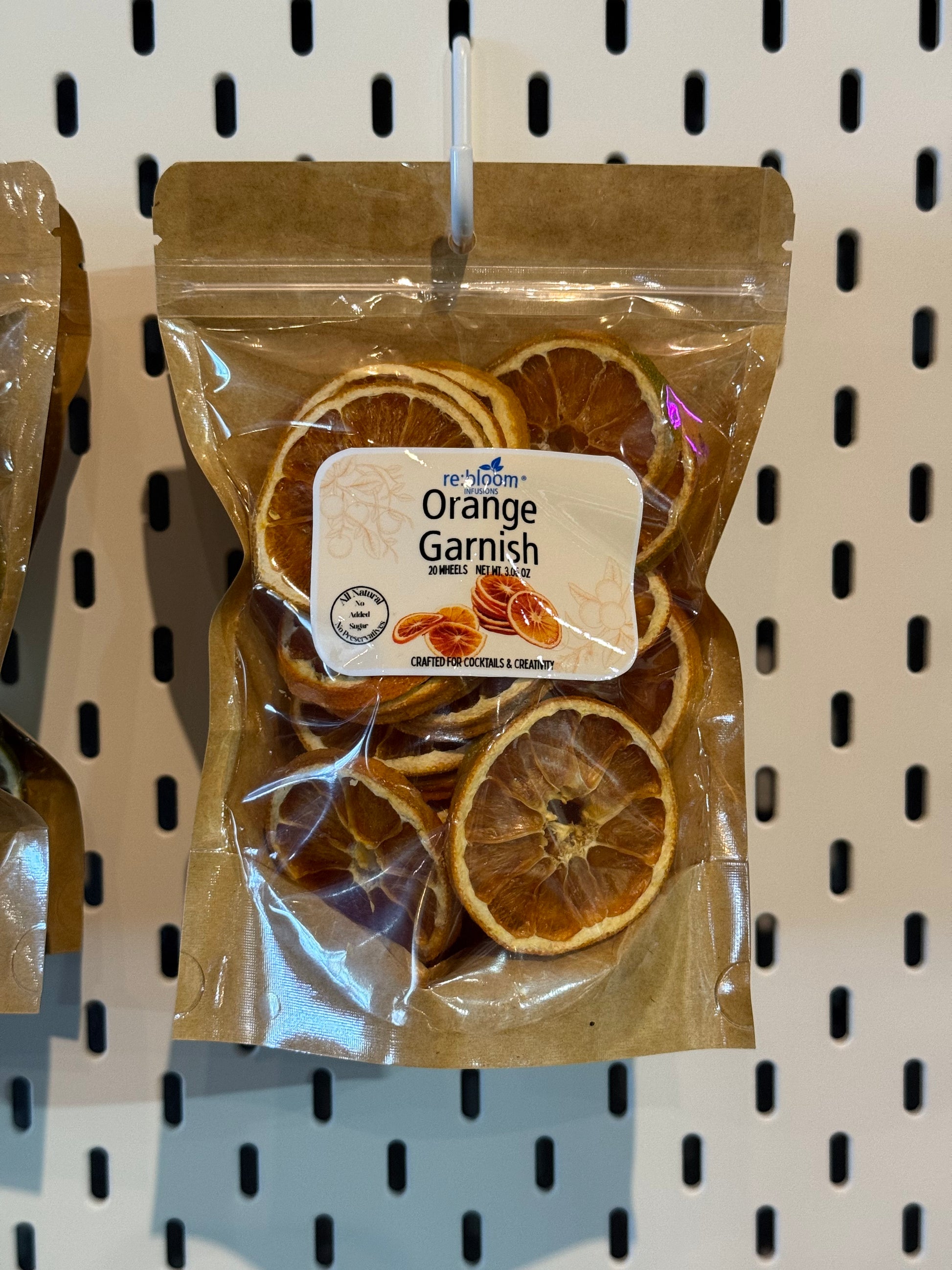 Packaged dried orange slices with a label on a peg board white background