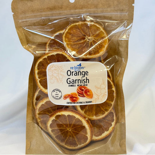 A clear resealable pouch of re:bloom Orange Garnish, showing dried orange slices inside with a white and blue label on a light neutral background.
