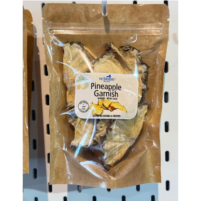 Packaged pineapple garnish with visible re:bloom Infusions label hanging on a pegboard display.