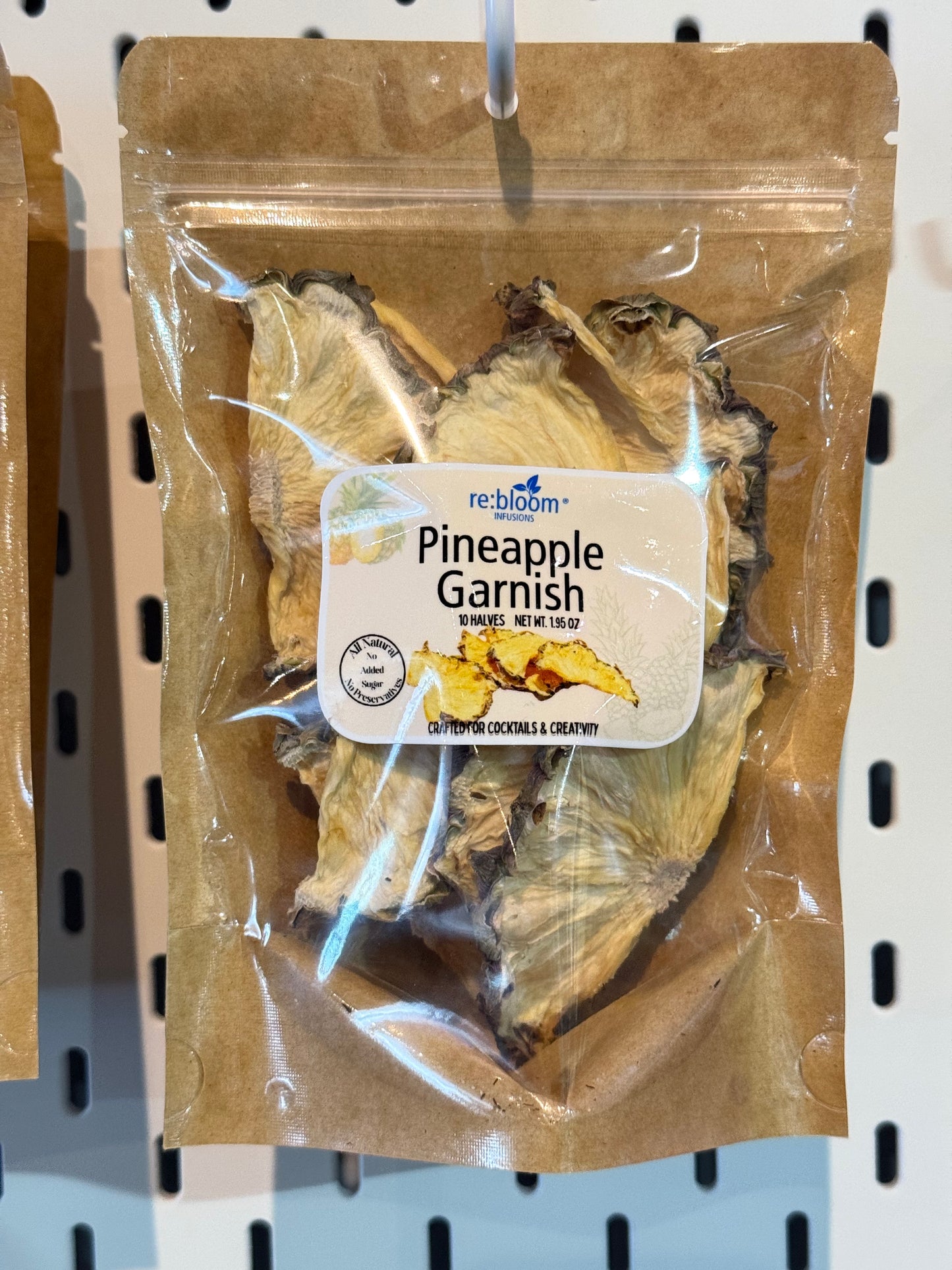 Packaged pineapple garnish with a label on a peg board