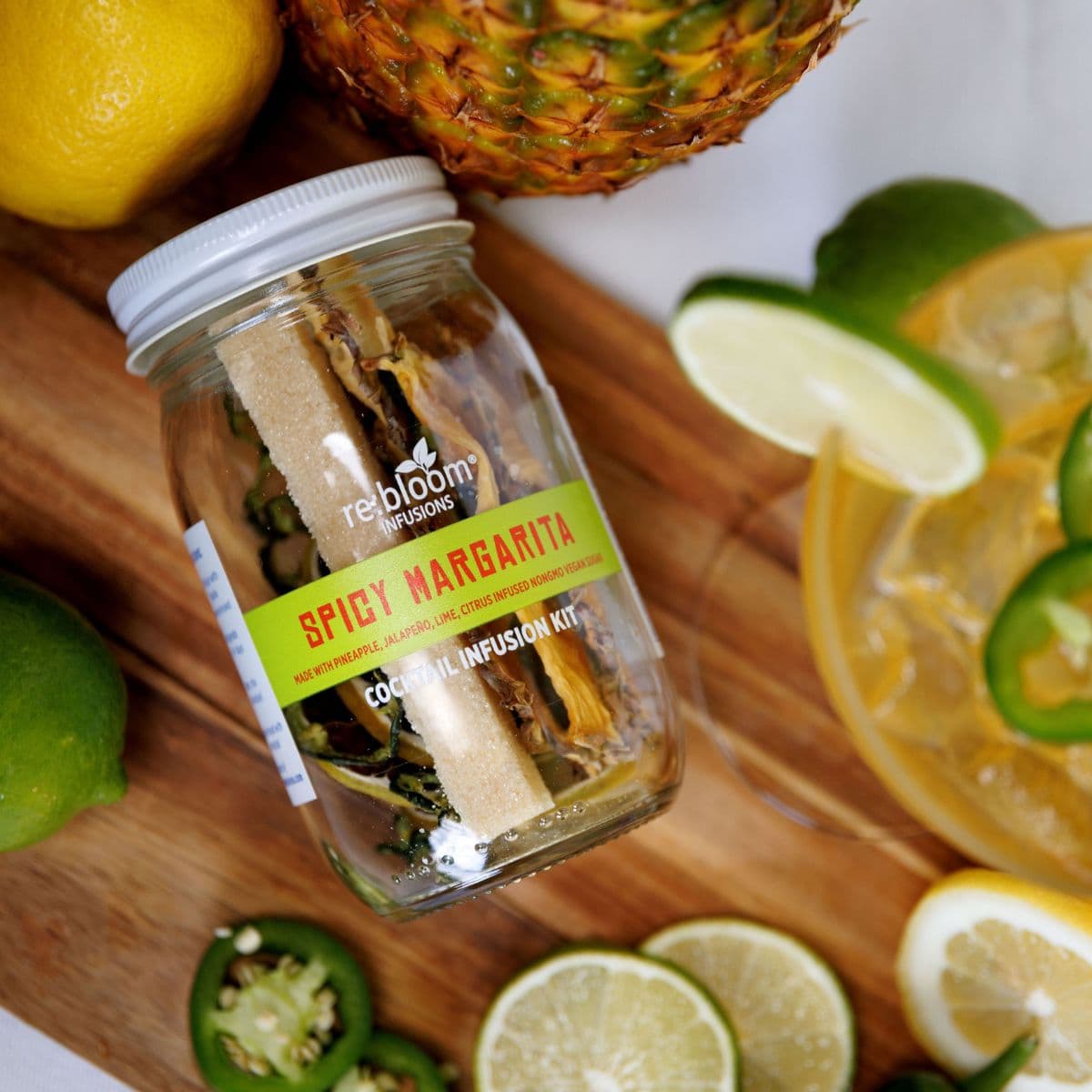 Spicy Margarita infusion kit with lemons, limes, and jalapeños on a wooden surface
