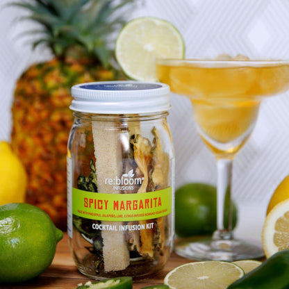 Spicy Margarita cocktail infusion kit with a glass of margarita, pineapple, lemon, and lime in the background.