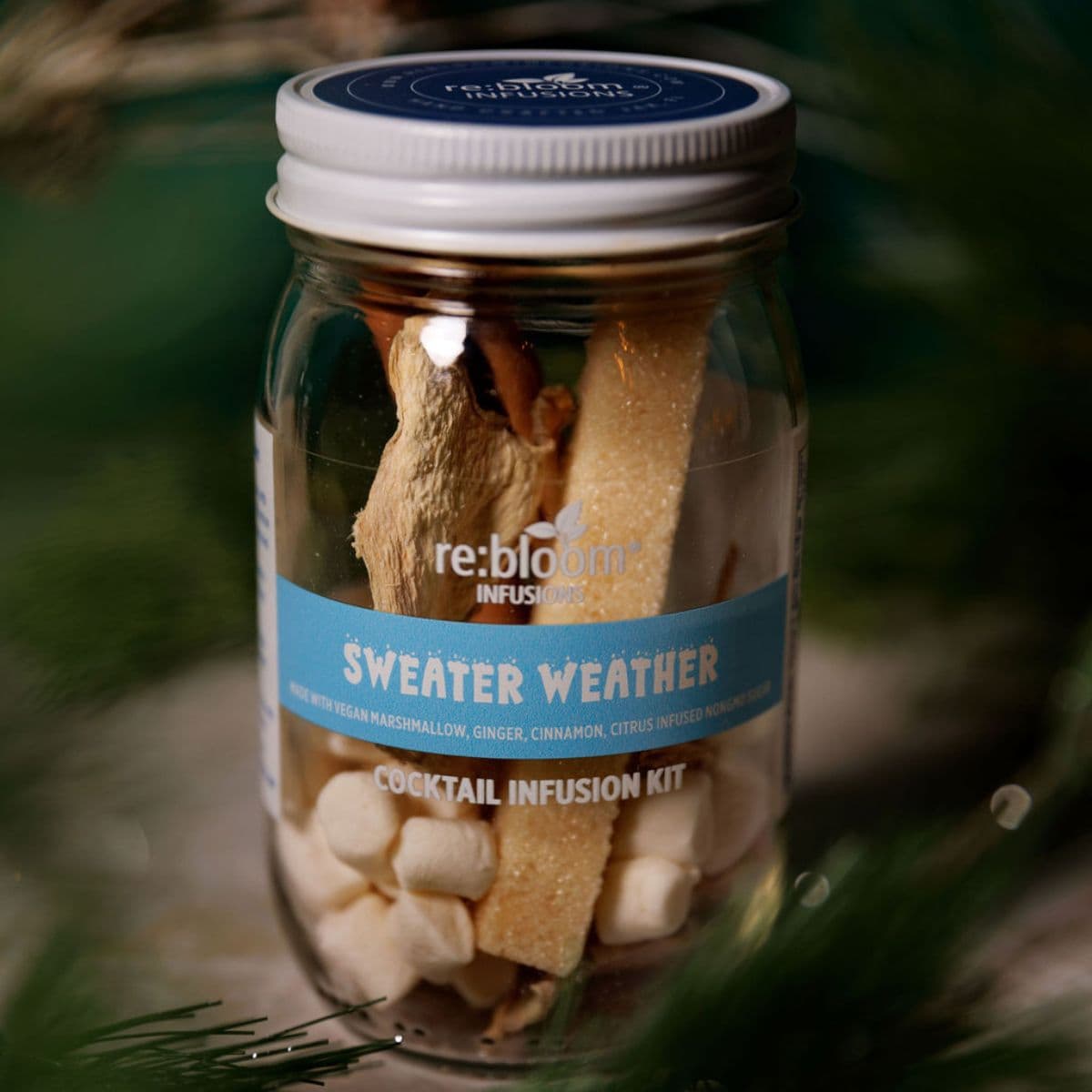 Jar of 'Sweater Weather' cocktail infusion kit with visible ingredients and branding on a green background.