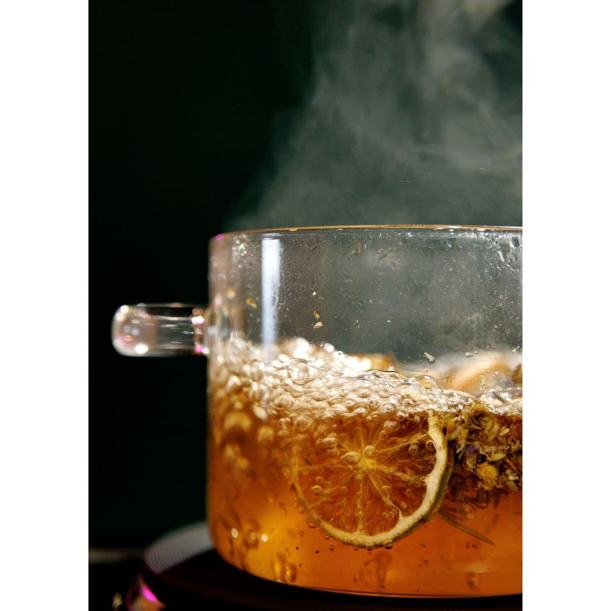 Steaming Lavender Haven simmer pot with citrus slices, lavender, and herbs in a glass pot for home fragrance.