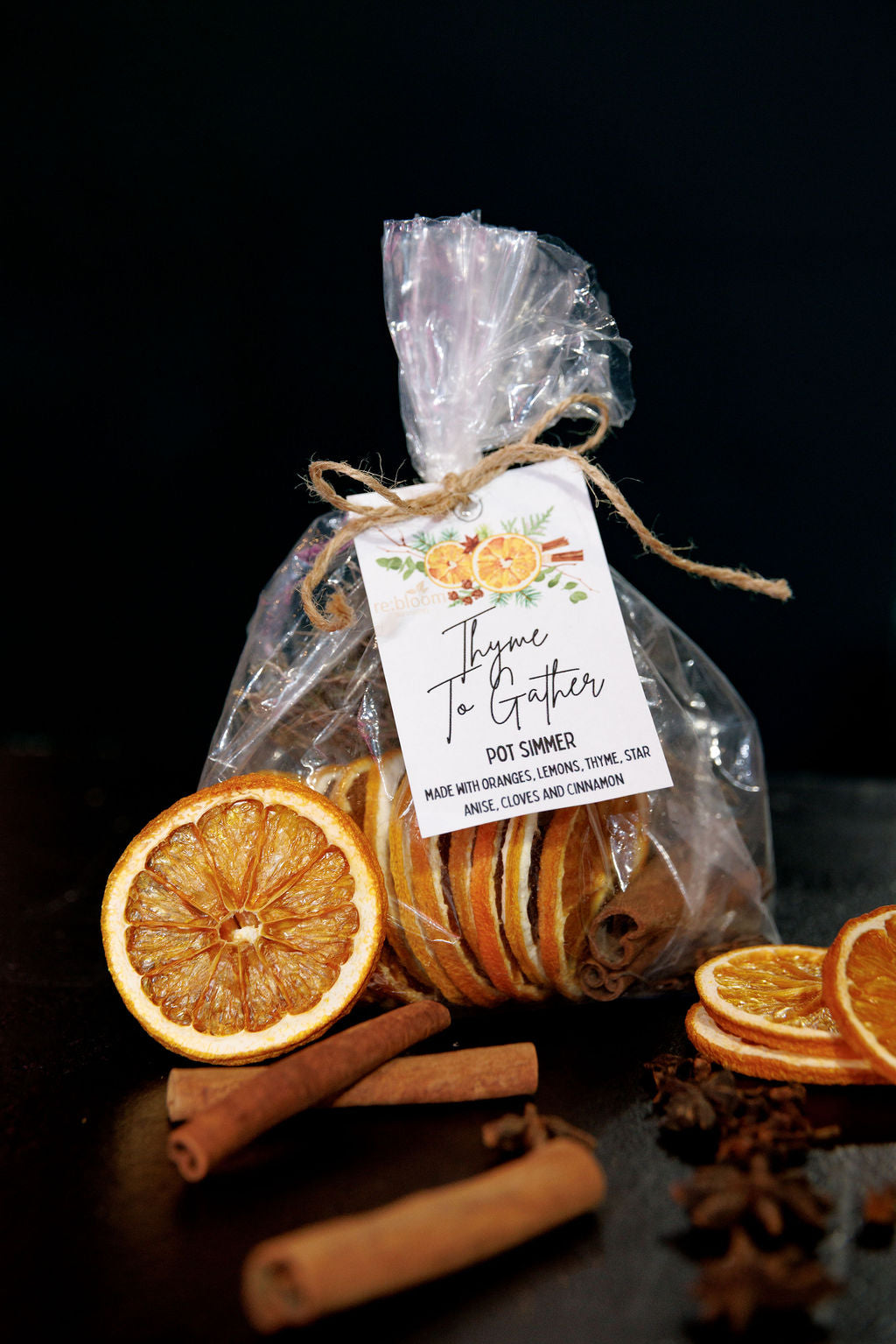 Bag of simmer pot ingredients  with cinamon sticks and orange slices on a dark surface