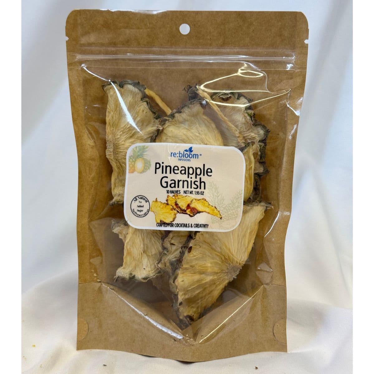 Packaged dried pineapple garnish with visible re:bloom Infusions label on a white background.